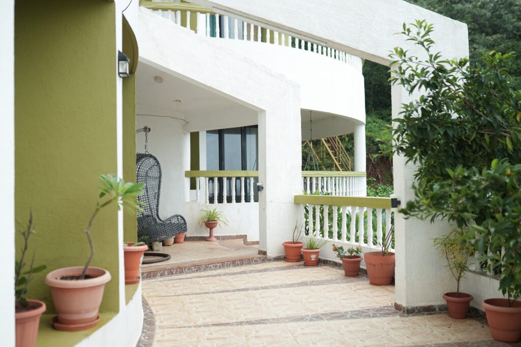 Private villa patio at Villa Infinity in Dapoli with potted plants, white arches, and cozy swing chair